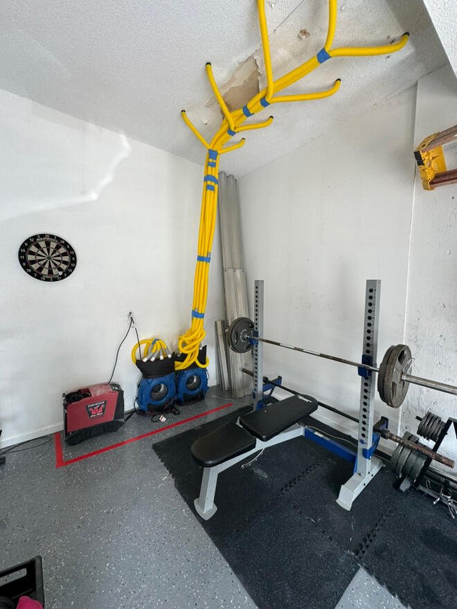 Yellow injection drying hoses connected to a wet garage ceiling